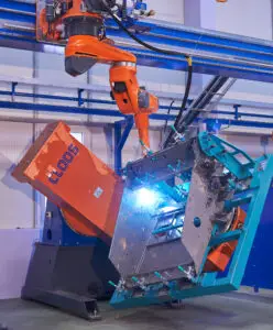 CLOOS robotic welding system in operation, showcasing advanced automation technology as it welds a complex metal assembly with precision and bright sparks.
